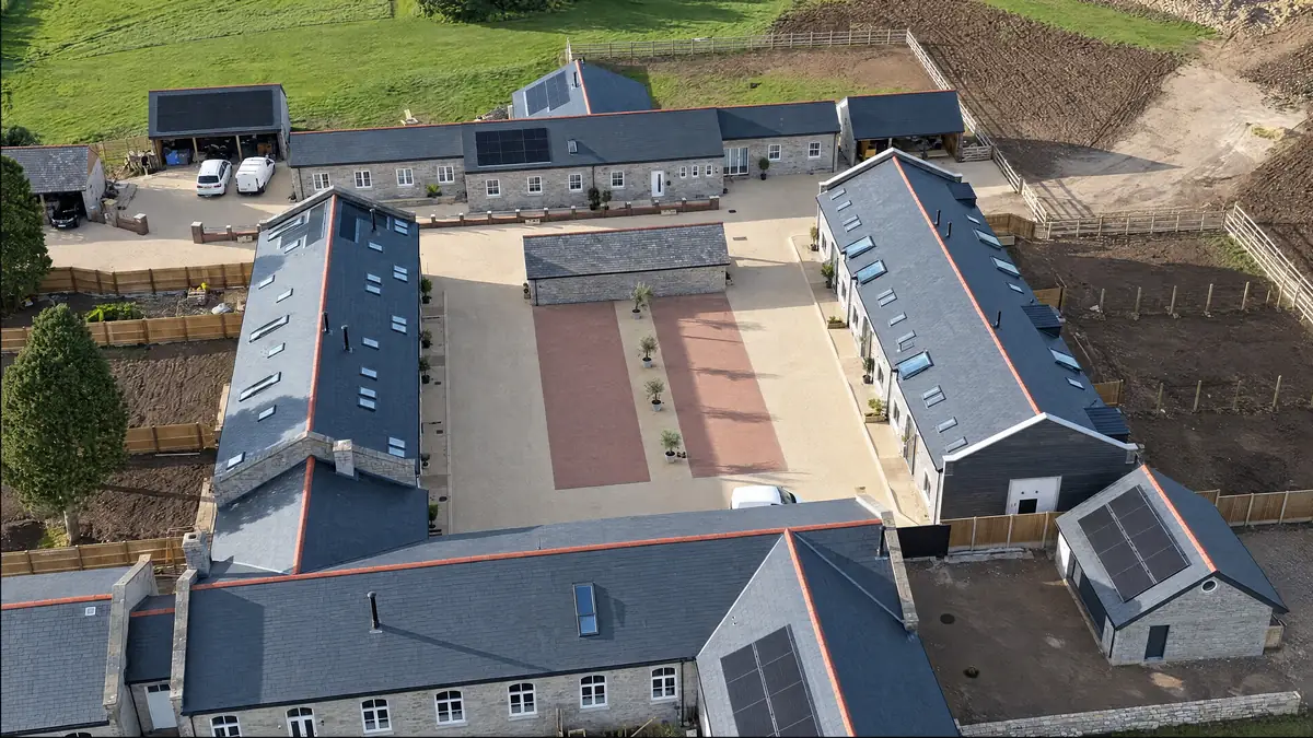 Aerial view of a barn conversion courtyard with new slate roofs and solar panels
