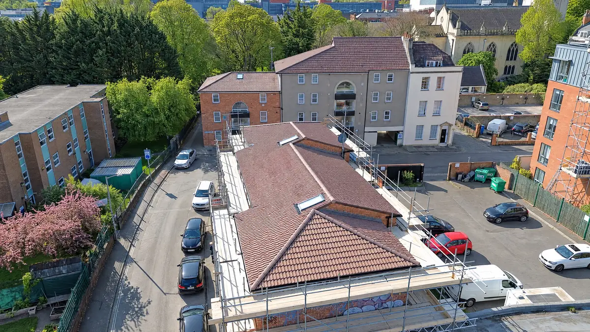 Aerial view of a commercial building with a new tiled hip roof and full scaffold