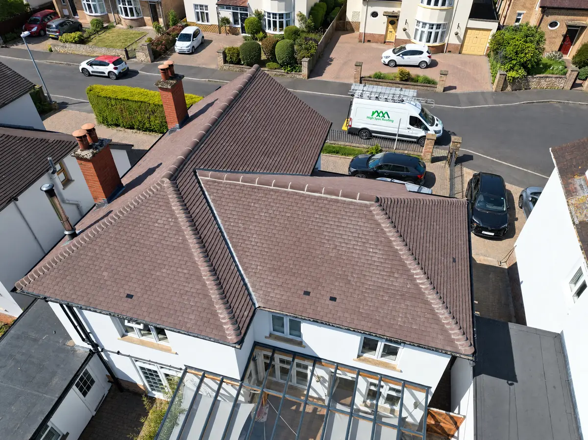 Aerial view of a newly re-tiled hip roof with the High Spec Roofing van parked outside