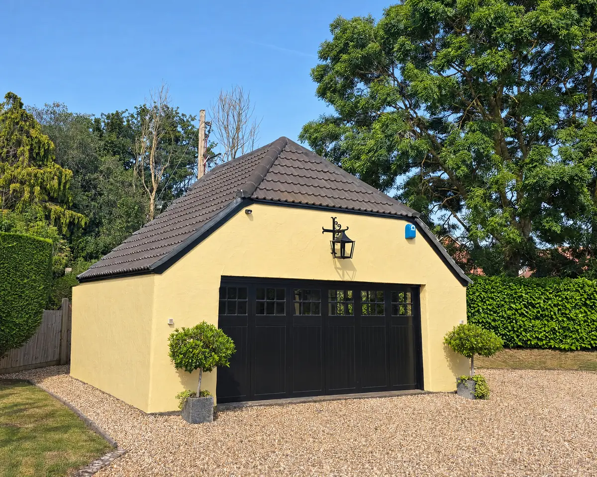 Detached garage re-roofed in brown tiles with yellow rendered walls